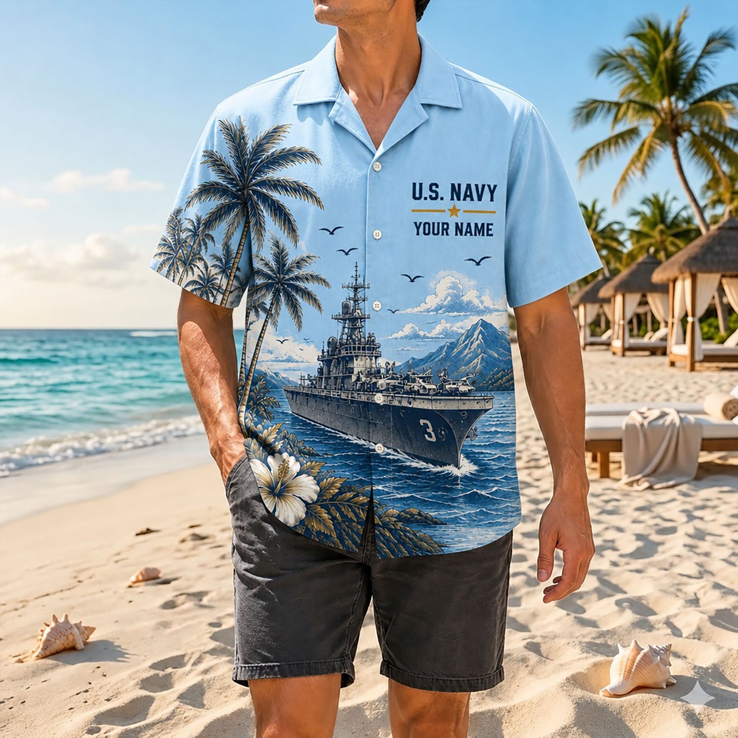 Full-body beach lifestyle image of a man wearing the personalized US Navy USS Kearsarge LHD-3 light blue tropical shirt with black shorts