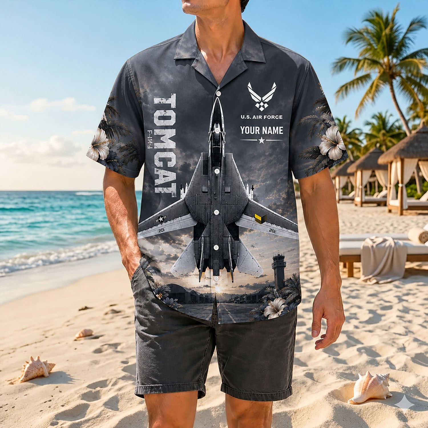 Full-body shot of a man modeling the vintage charcoal grey F-14 jet shirt on a sandy coast paired with matching casual grey beach shorts