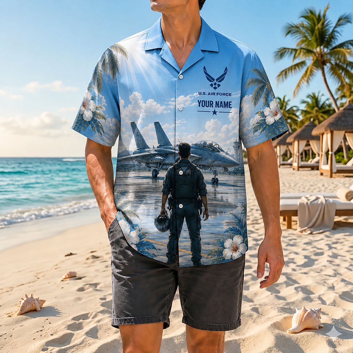 Full-body shot of a man modeling the custom name fighter jet holiday shirt on a sandy shore with casual grey shorts