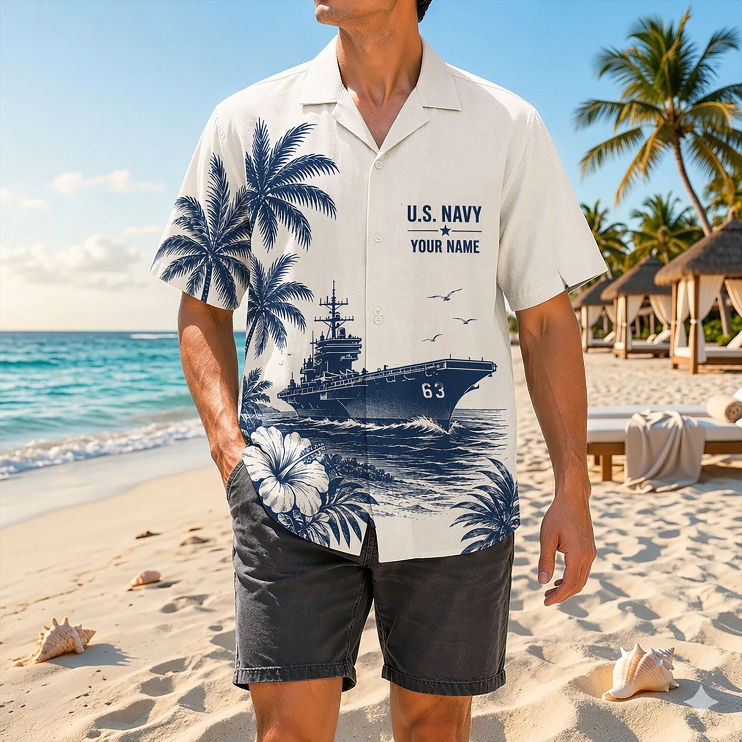 Full shot of a male model standing on sand wearing the custom name USS Kitty Hawk CV-63 shirt paired with charcoal grey shorts
