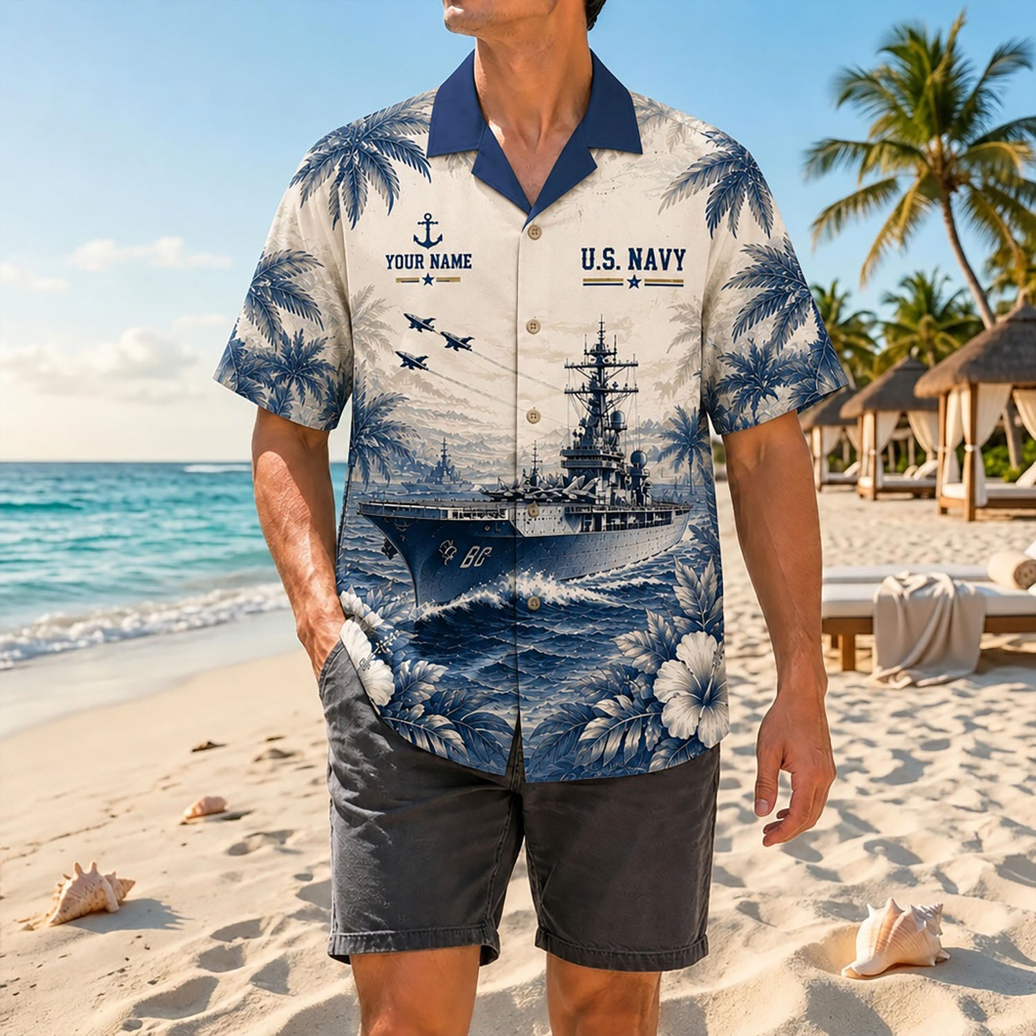Full shot of a male model standing on sand wearing the custom name USS Saratoga CV-60 navy collar shirt paired with grey shorts