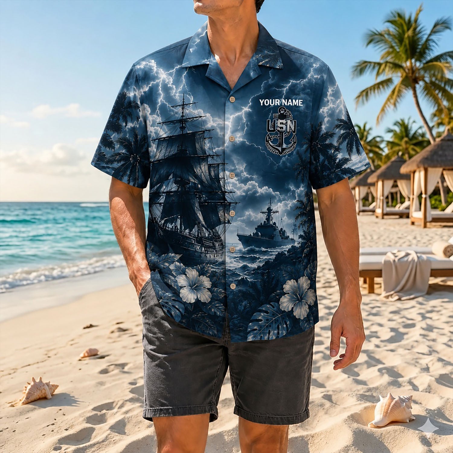 Full shot of a male model standing on the sand wearing the custom name US Navy battleship shirt paired with faded black shorts