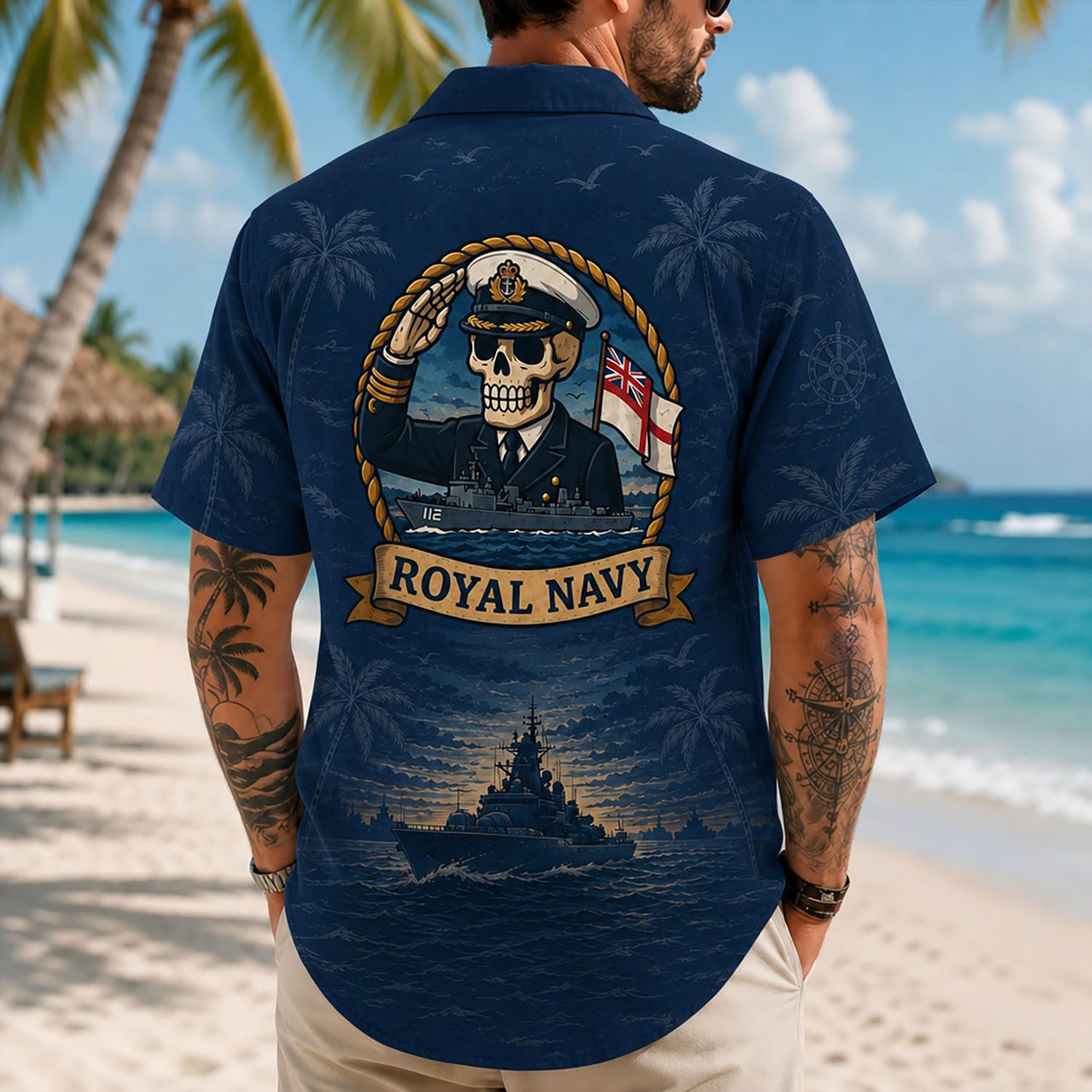 Back view lifestyle of a man on a beach showing the detailed British naval skull emblem and warship horizon print