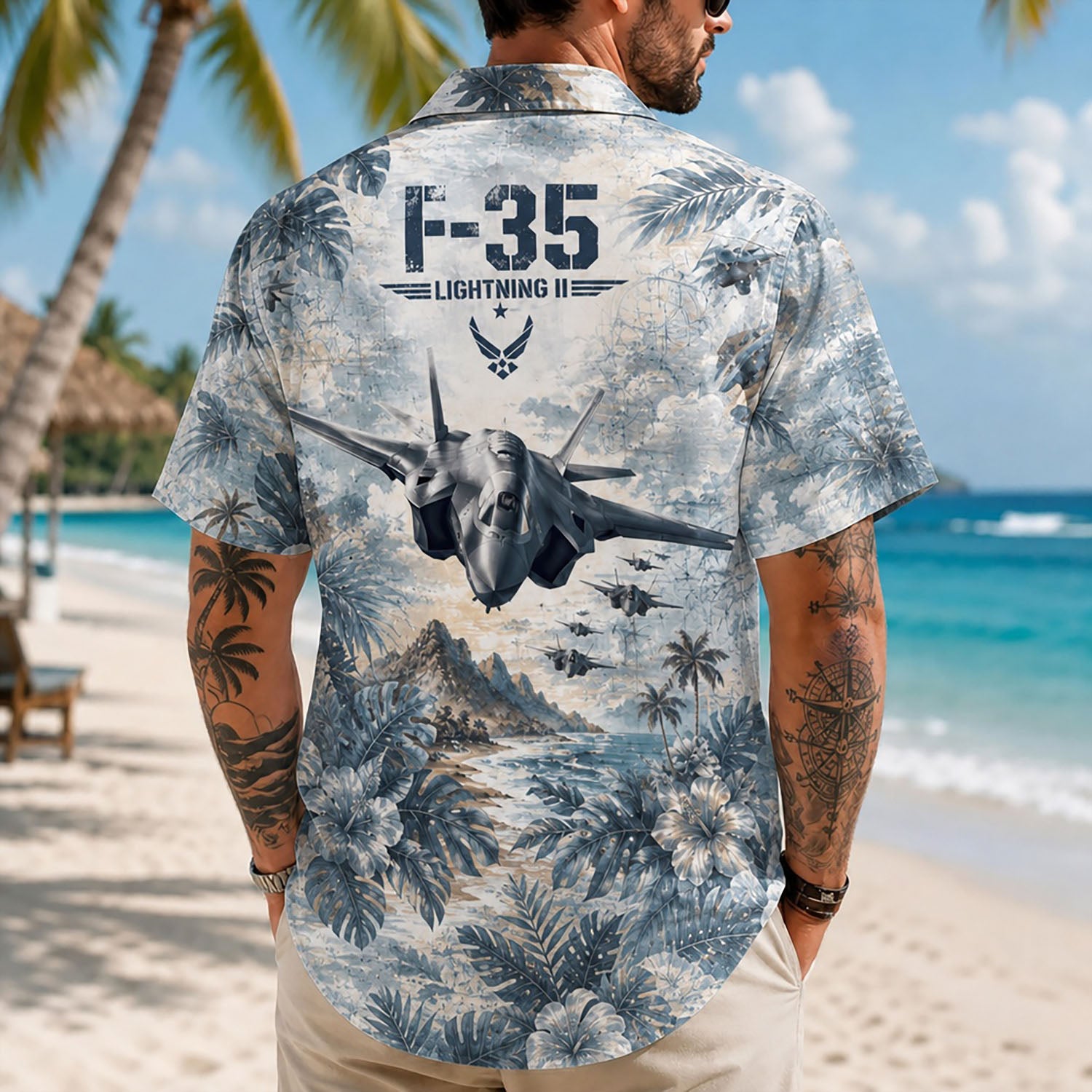 Back view lifestyle of a man showcasing the bold F-35 jet graphics, tropical palm trees, and military insignia on sand
