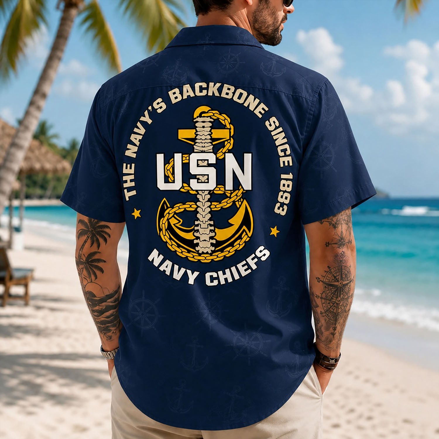 Back view lifestyle of a man on a beach showing the detailed USN anchor spine emblem and navy background texture