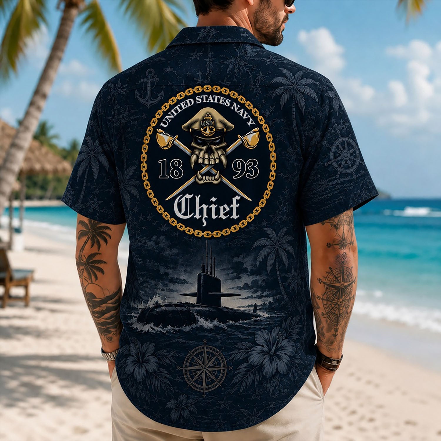 Back view lifestyle of a man on a beach wearing the custom Navy Chief shirt showing the detailed 1893 skull badge and submarine ocean print
