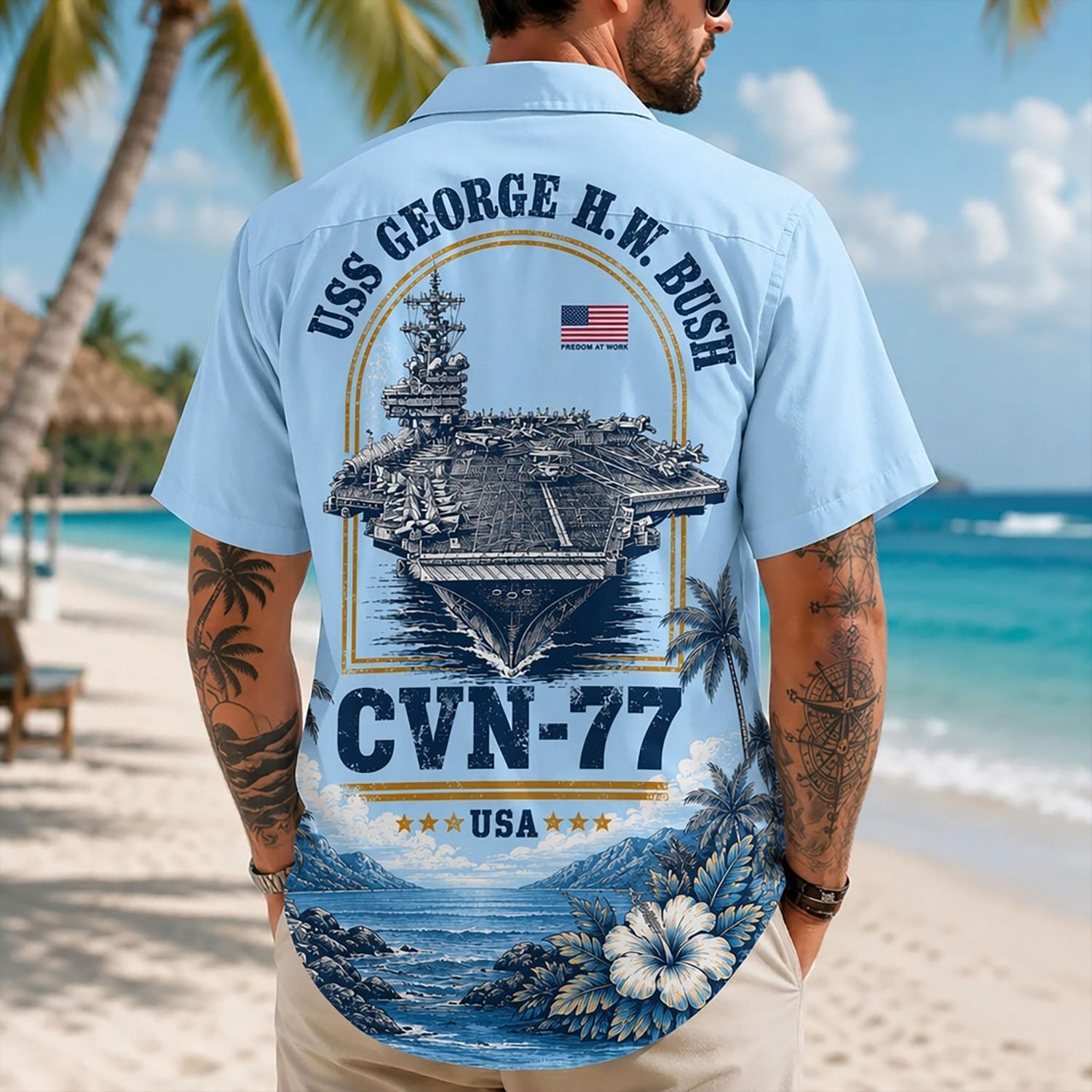 Back view lifestyle of a man on a beach wearing the custom veteran shirt showing the large USS George H.W. Bush CVN-77 emblem print